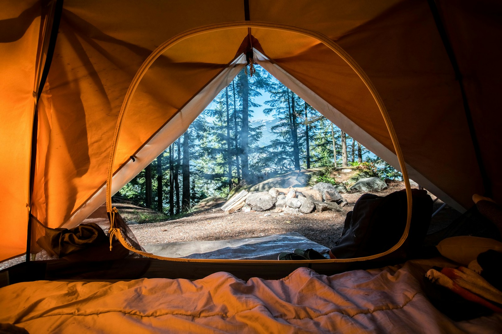 Orange dome 2 person tent pitched among green trees