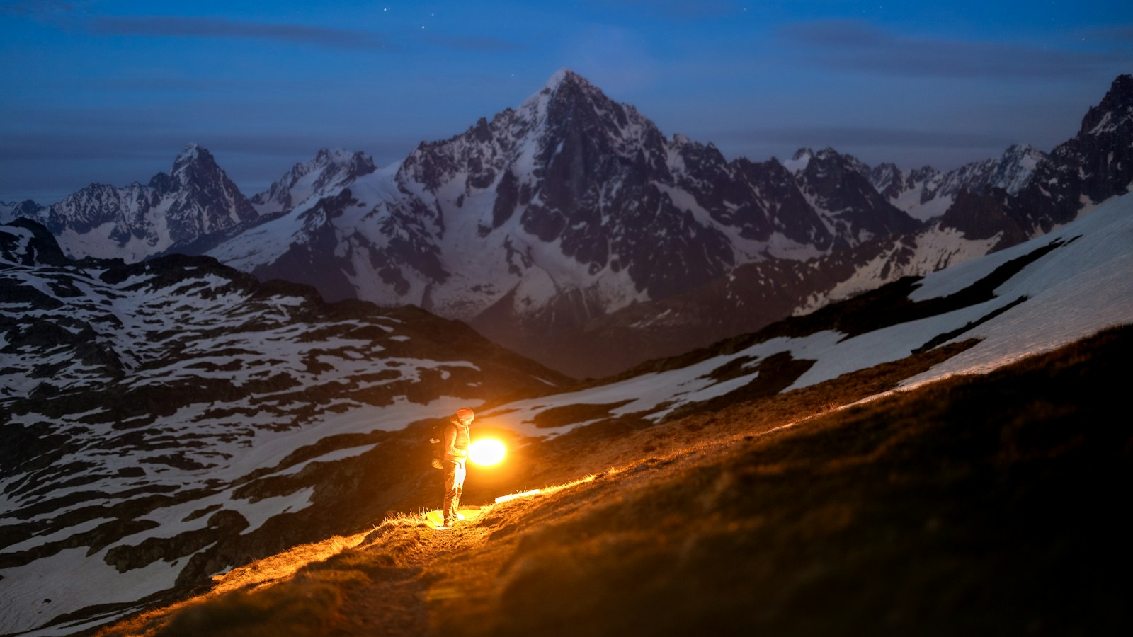 Lone hiker using one of the best headlamps for hiking on a mountain path at night