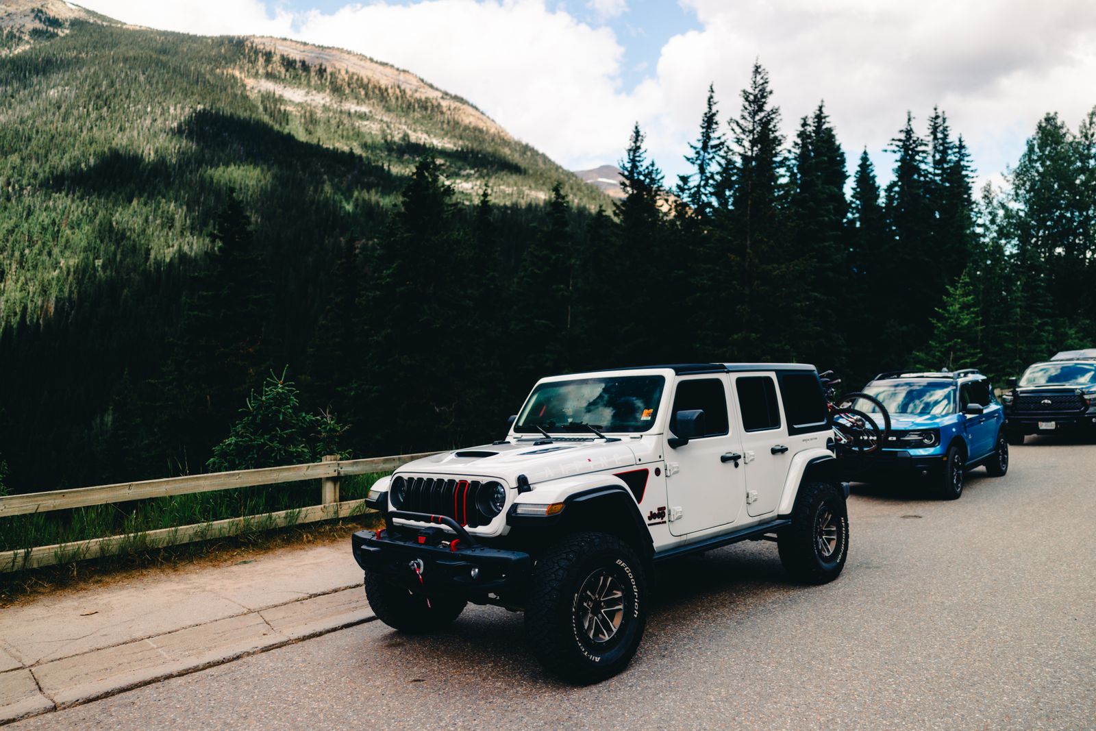 Car hiking trip with an off-road vehicle parked beside a forest road below the mountains