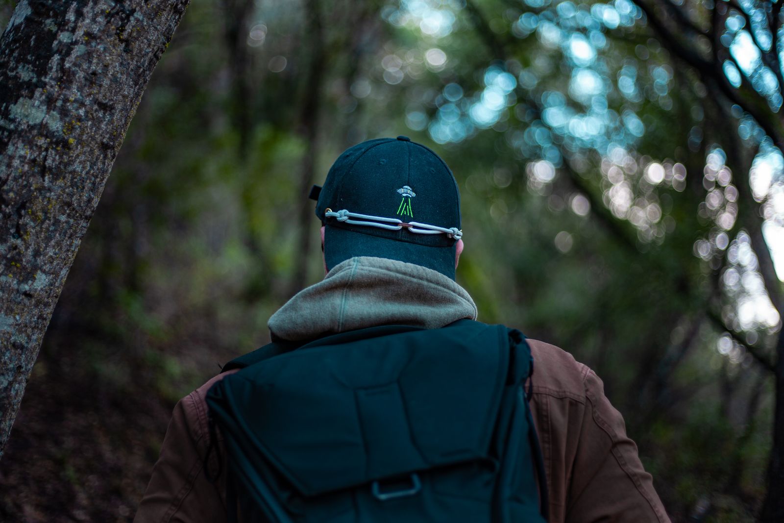 Hiker walking a shaded forest trail, where a cap or bucket hat for hiking is often enough