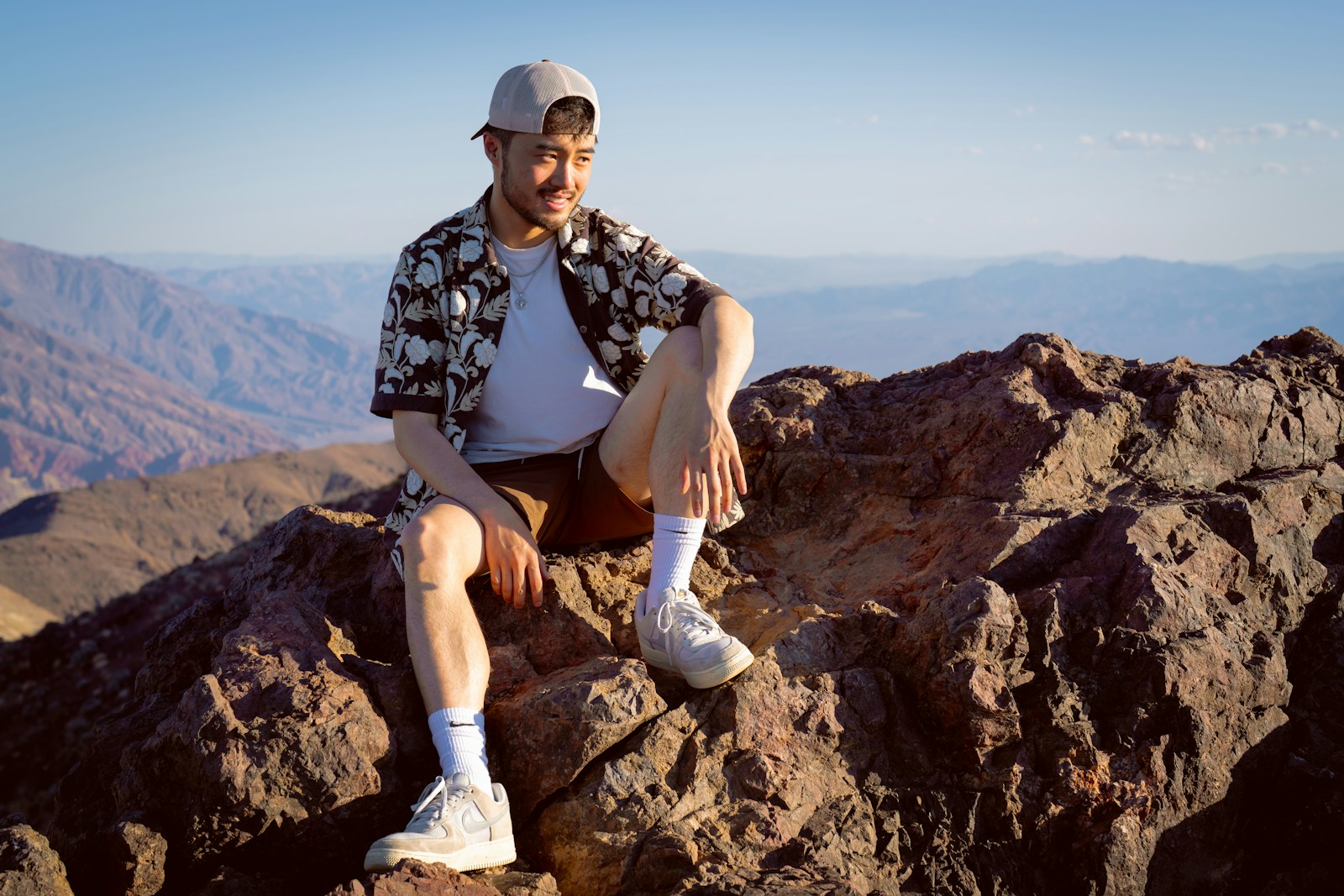 Hiker in a cap resting on a rocky mountain summit after a long day, when hiking hats need care