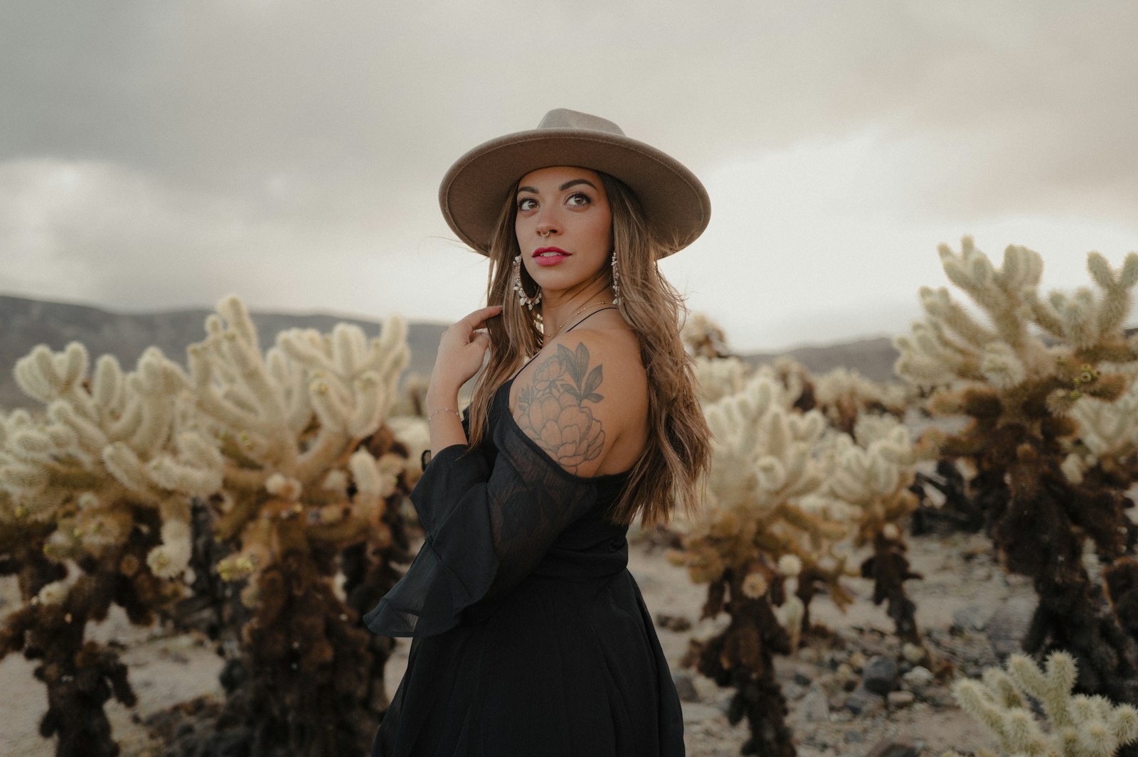 Woman in a light-colored hat among desert cacti, showing which hiking hats for women suit hot sun