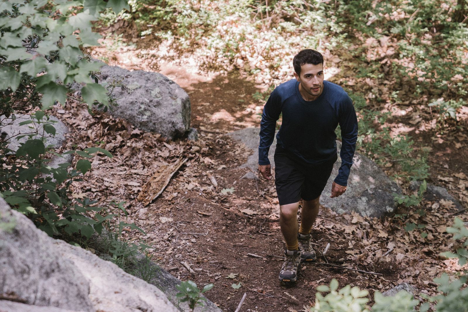 Man in a long-sleeve top hiking a rocky forest trail, a simple hiking hoodie mens layering example