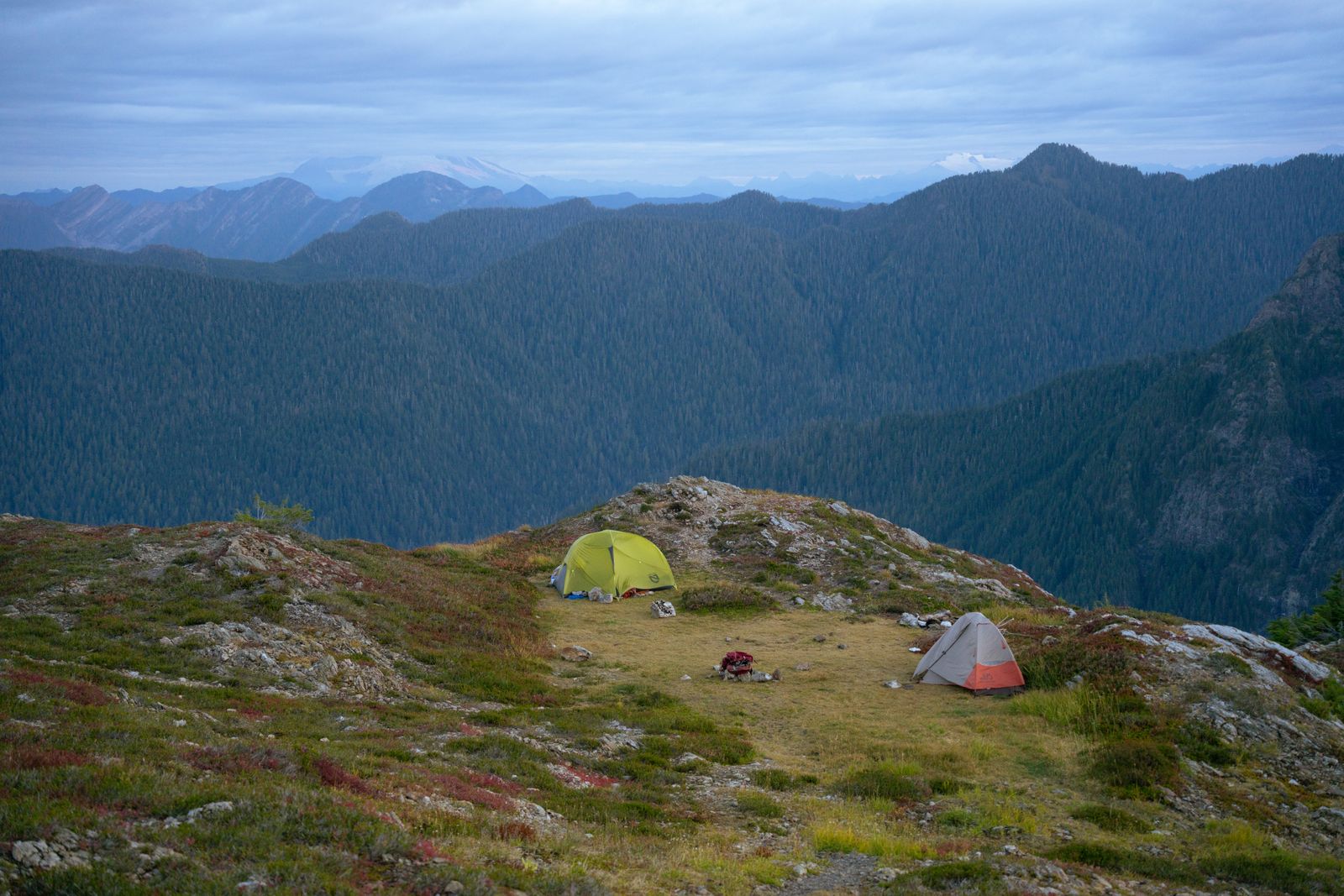 Two backpacking tents pitched below mountain peaks on a Naturehike hiking style trip