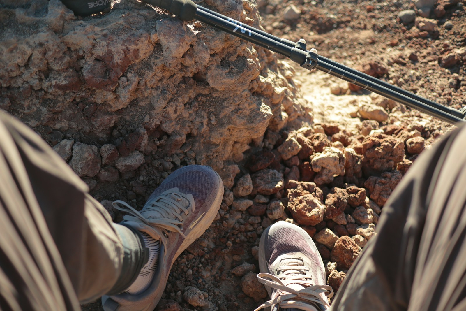 Hiking shoes and a trekking pole on a rocky trail, useful context for choosing night hiking boots