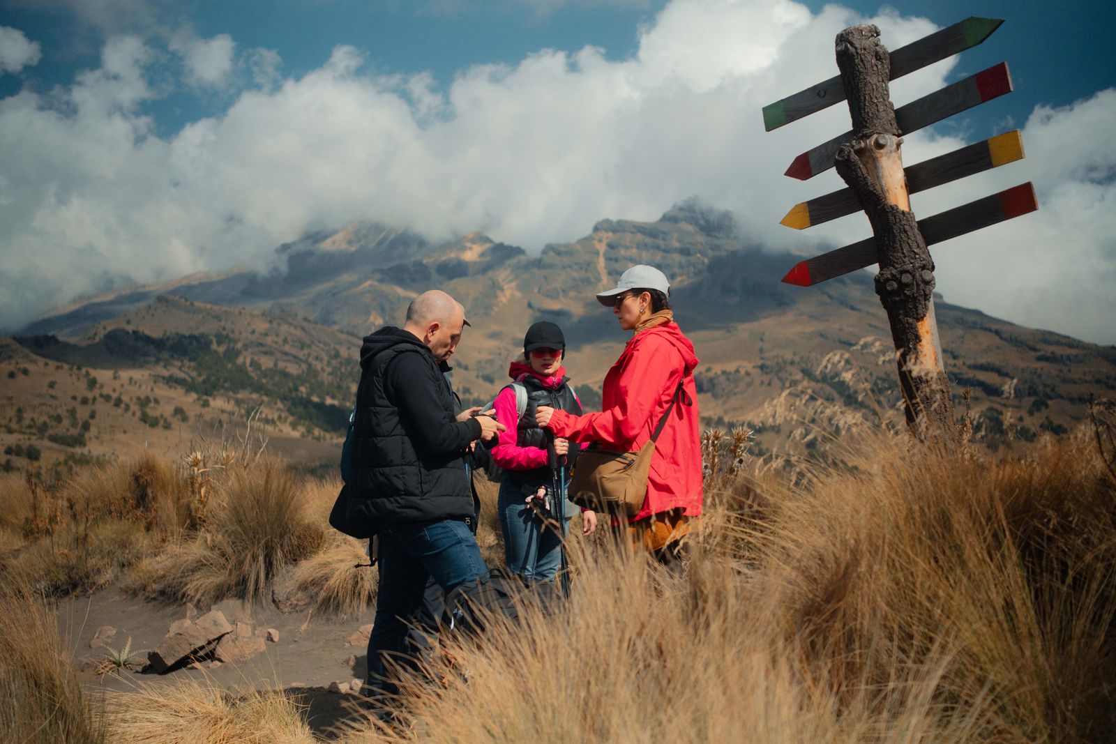 Group of hikers at a mountain signpost ready for a quiz hiking challenge