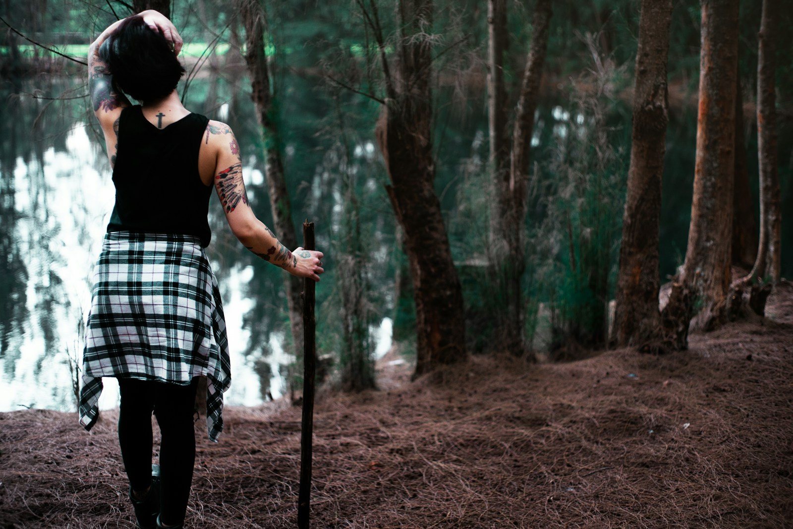 Woman holding a walking stick beside a lake, an example of walking sticks for women